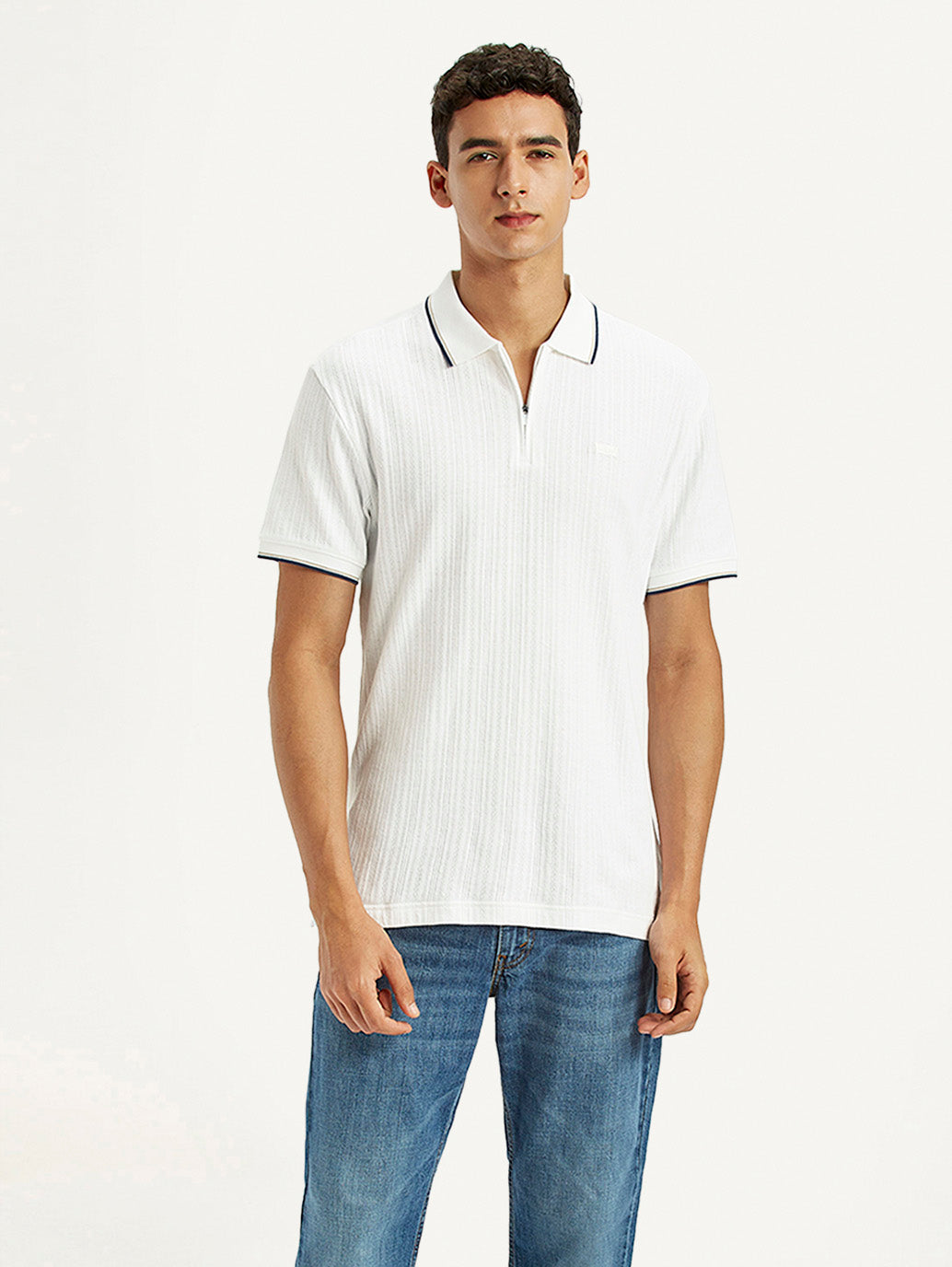 Men's solid white slim fit polo t-shirt by Levis, showcasing a classic collar and short sleeves in a stylish setting.