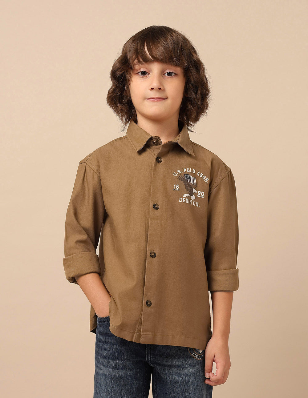 U.S. Polo boys' shirt featuring a classic design, with short sleeves and a collar, displayed on a hanger.